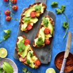 harissa, scrambled eggs and avocado toasts on a blue background