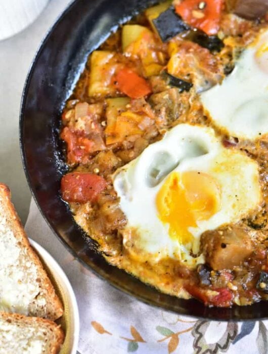 ratatouille with poached eggs in a black pan