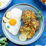 zucchini and corn fritters with fried egg on a blue plaze