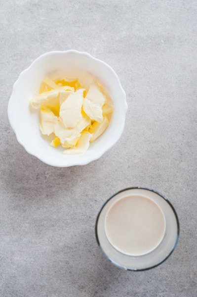 Drożdże wymieszane z mlekiem w szklance, masło w miseczce
