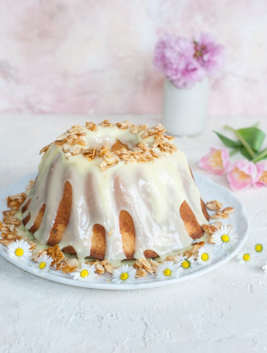 almond bundt cake on a white plate, covered with chocolate glaze and flaked almonds