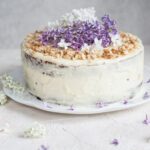 carrot layer cake with cream cheese frosting decorated with flowers and nuts