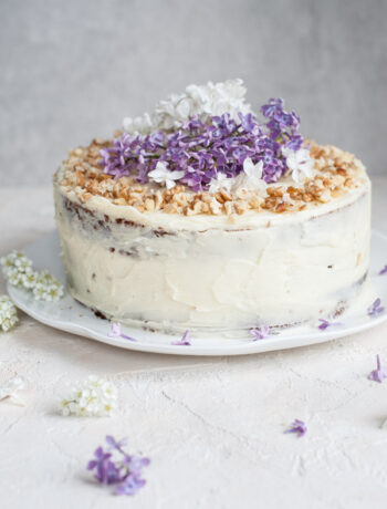 carrot layer cake with cream cheese frosting decorated with flowers and nuts