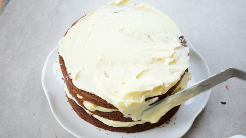 carrot cake is being frosted with cream cheese frosting