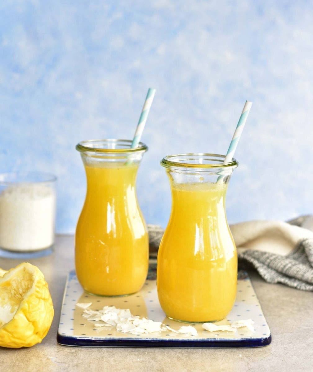 pina colada lassi in two jars on a white and blue chopping board