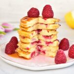 a stack of lemon ricotta pancakes with raspberries
