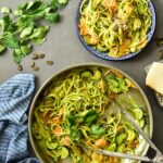Parsley pesto pasta with zucchini and carrots in a pan.