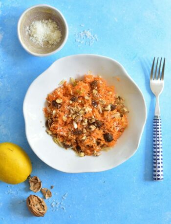 white plate with carrot apple salad on a blue background