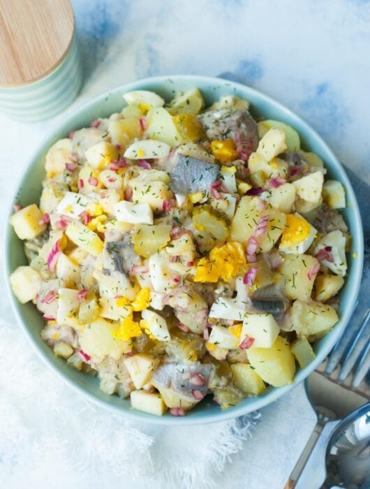herring salad with potatoes and eggs in a green bowl