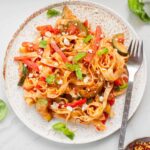 tagliatelle pasta with zucchini, bell pepper and feta on a white plate