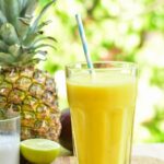 pineapple mango coconut smoothie in a glass on a wooden board