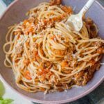 szybkie spaghetti z mięsem i sosem ze świeżych pomidorów nabite na widelec w fioletowej misce
