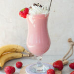 strawberry banana milkshake in a high glass with whipped cream