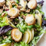 Apple celery salad with walnuts and goat cheese on a white plate.