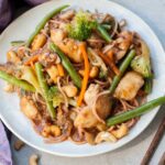 chinese plum sauce noodles with chicken and vegetables on a white plate