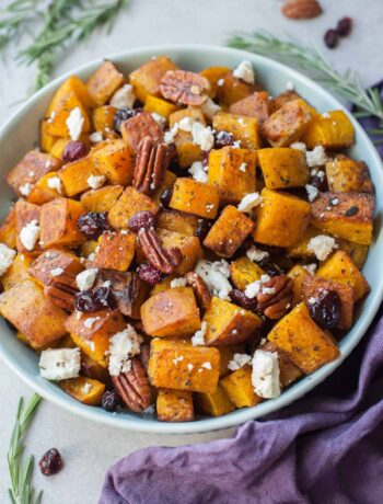 Roasted butternut squash with cranberries, pecans, rosemary and feta cheese in a blue bowl.