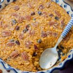 A close up picture of baked pumpkin oatmeal in a baking dish with a serving missing.