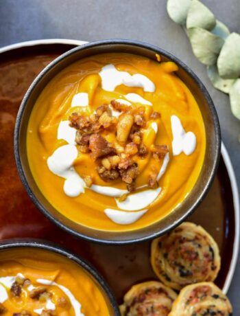 Pumpkin chestnut soup in a black bowl topped with yogurt and caramelized chestnuts.
