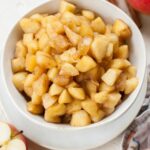 Sauteed cinnamon apples in a white bowl.