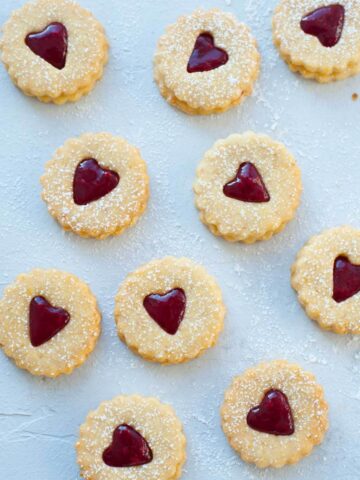 Raspberry Linzer cookies on a blue background.