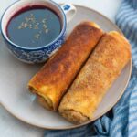 Polish croquettes on a brown plate with a cup of borscht.