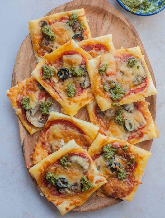 Puff pastry pizza bites on a wooden tray.