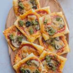 Puff pastry pizza bites on a wooden serving tray.