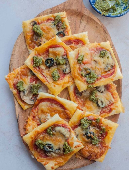 Puff pastry pizza bites on a wooden serving tray.