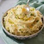 Sour cream mashed potatoes with chives in a white-blue bowl.