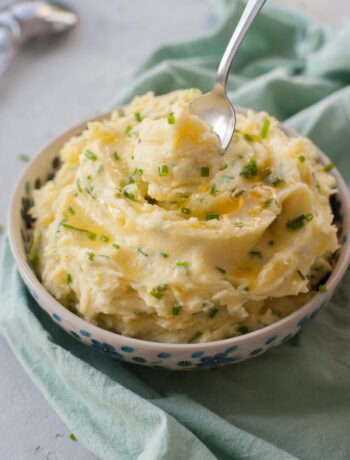 Sour cream mashed potatoes with chives in a white-blue bowl.