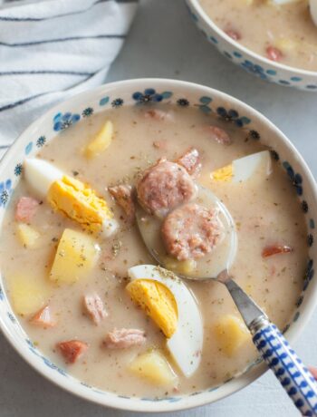 Żurek soup with potatoes and eggs in a white-blue bowl.