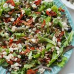 Sun-dried tomato salad on a green plate.