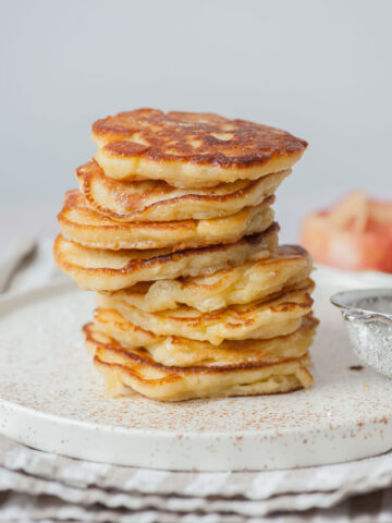 A stack of apple pancakes on a white plate.