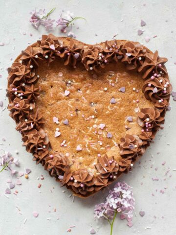 Heart-shaped chocolate chip cookie cake on a grey background.