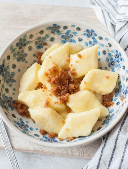 Kopytka with buttered breadcrumbs in a white-blue bowl.