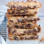 A stack of 7-layer magic bars on a piece of parchment paper.