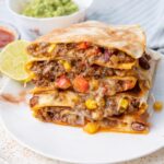 A stack of ground beef quesadillas on a white plate.