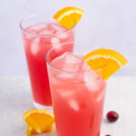 Two glasses with madras drink granished with orange slices.