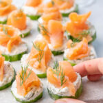 Smoked salmon appetizer with cucumbers and cream cheese on a stone board.