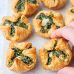 Spinach puffs on a grey stone board.