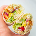 Greek chicken wraps held in a hand.