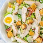 Chicken Caesar salad in a white bowl.