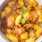 Chicken and gnocchi in creamy butternut squash sauce in a white bowl.