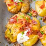 Loaded smashed potatoes on a baking sheet.