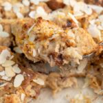 Panettone bread pudding in a baking dish and on a large spoon.