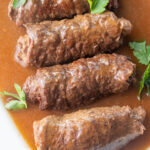 Rouladen with gravy on a white plate.