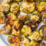 Smashed brussel sprouts on a white plate.