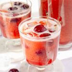 Two glasses and a pitcher with cherry lemonade.