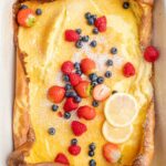 Dutch baby pancake in a white casserole dish topped with berries.