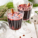 Two glasses with Glogg - Scandinavian mulled wine on a white board. Christmas decorations in the background.